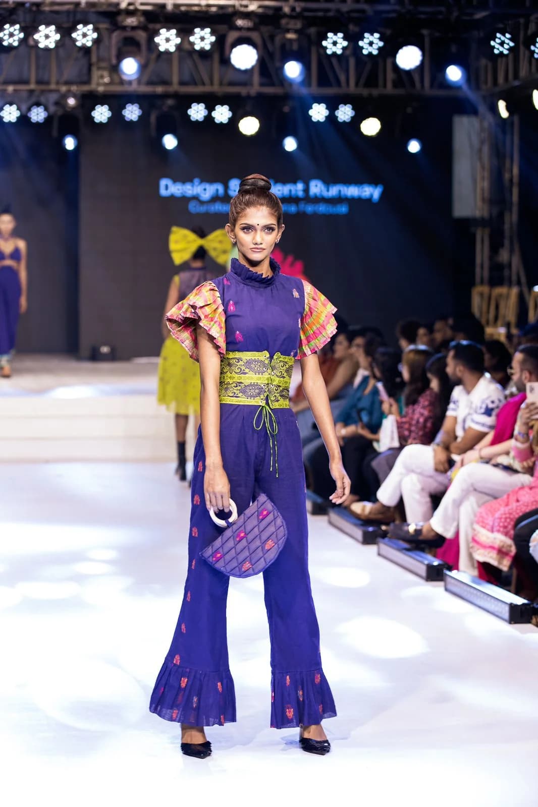 Arka Fashion Week runway look by Bangladeshi fashion designer Narin Juhi — purple and chartreuse two-piece with flared trousers