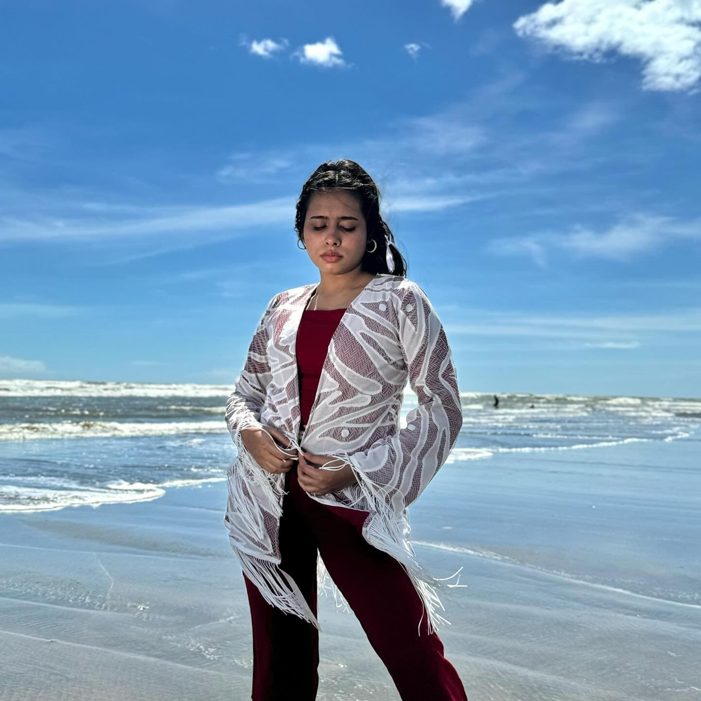 Sheer white patterned shirt with fringe sleeves over maroon